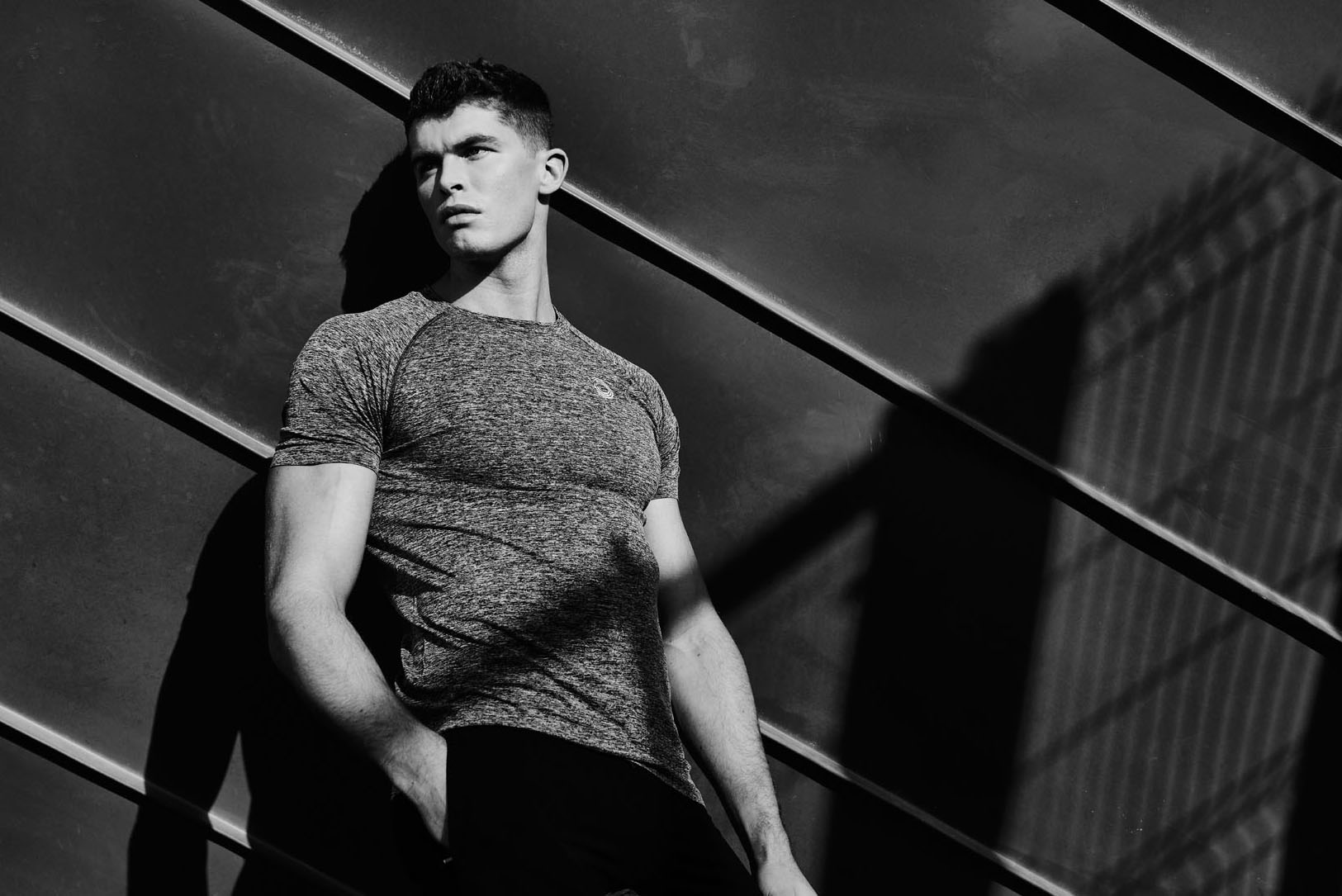 Fashion photography to launch the Bulk Wear brand. A male model stands near a metal fence.