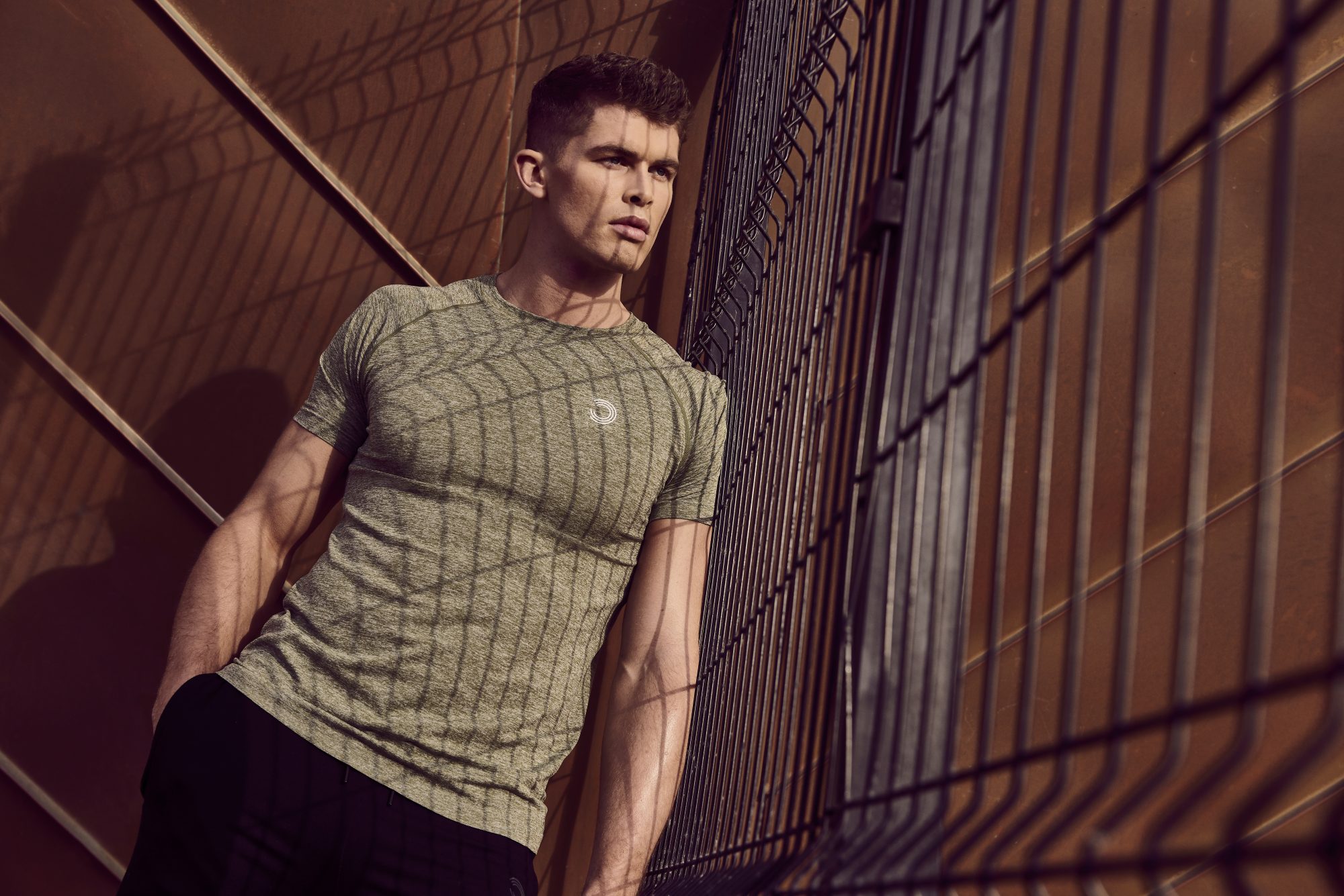 Fashion photography to launch the Bulk Wear brand. A male model stands near a metal fence.