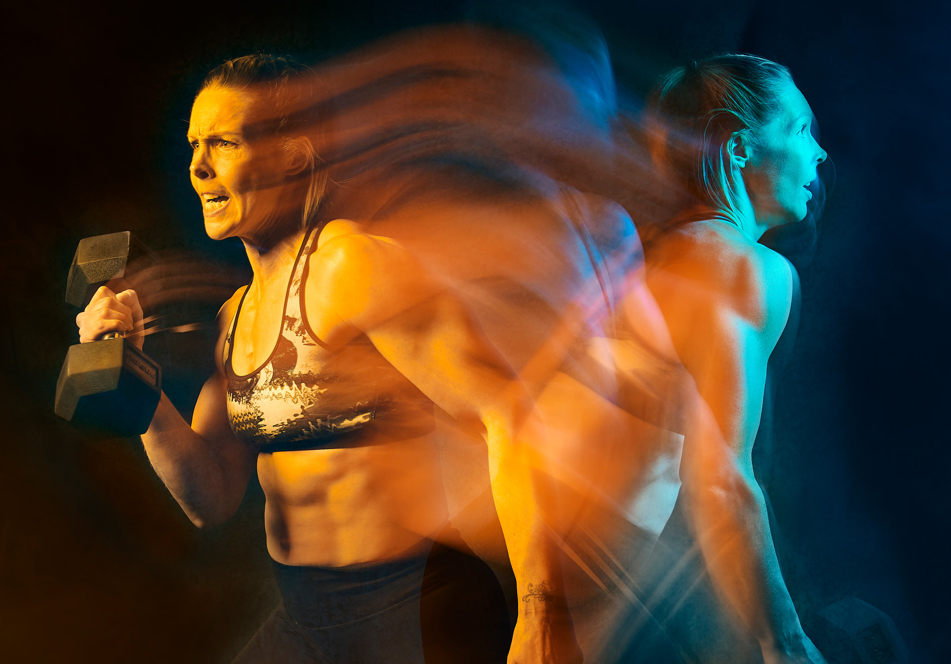 A long exposure image of a female athlete turning and lifting a dumbell