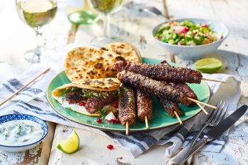 Lamb koftas and flat breads on a sunny outdoor table