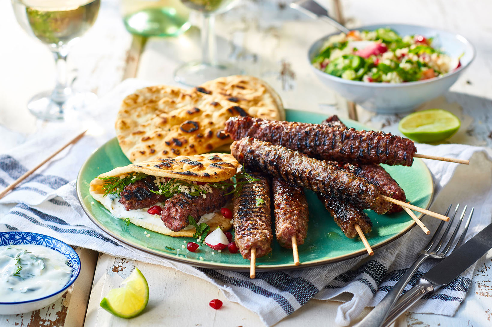 Lamb koftas and flat breads on a sunny outdoor table