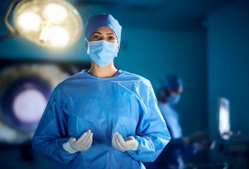 A female surgeon wearing scrubs in an operating theatre